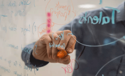Endeavor selecciona 102 empresas ampliadas para programa de aceleración. La imagen muestra a una persona escribiendo en un tablero transparente con un bolígrafo de color.